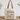 A cream canvas tote bag with brown leather handles, featuring a vintage-style graphic print that reads 'You had me at VINTAGE' above illustrated teacups, flowers, and retro objects. The bag is displayed on a wooden surface against a white wall with eucalyptus branches in the background.